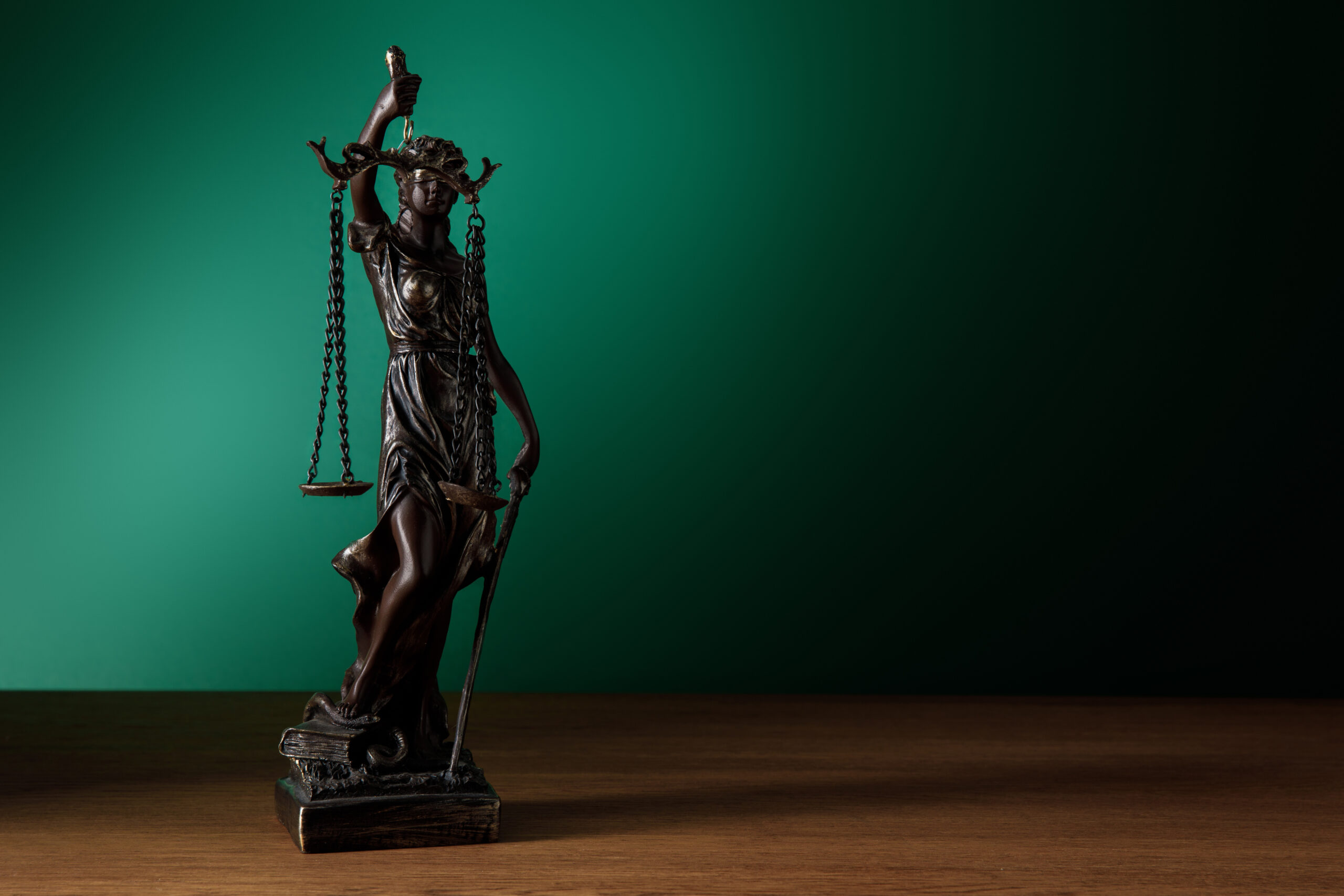 Statuette de la justice posée sur un bureau en bois